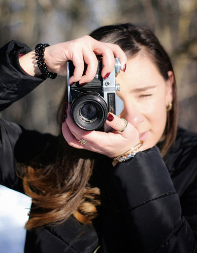 Woman holds camera front of eye to focus