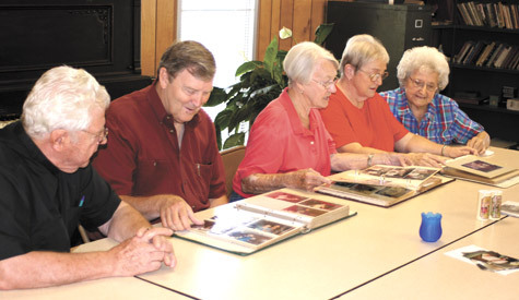 Father Thomas Keller (from left) observes parishioners Mike Dolan, Martha Melkovitz, Donna Busick and Edith Workman get lost in fond memories looking through old photo albums at Holy Trinity Church in England July 29.