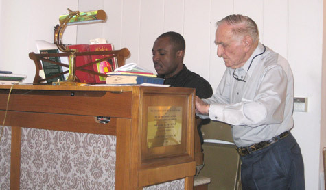 Carl Chambers of Horseshoe Lake writes down the song numbers for Saturday Mass at St. Mary of the Lake Church as Father Athanasius Okeiyi practices playing the music on the organ.