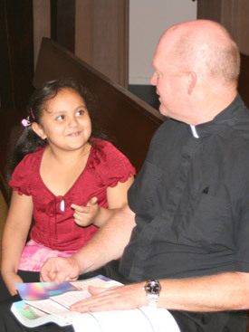 Father Phillip Reaves goes over a first Communion lesson with 7-year-old Karla de los Angeles Meja after Sunday afternoon Mass Nov. 15, at Holy Child of Jesus Church in Dumas.