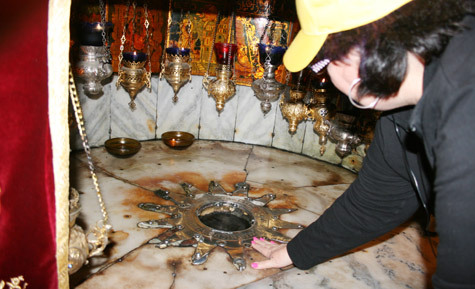 During Arkansas Catholic's pilgrimage to the Holy Land in March, Christie Powell of Morrilton touches the place in the Basilica of the Nativity in Bethlehem where Jesus was believed to have been born.