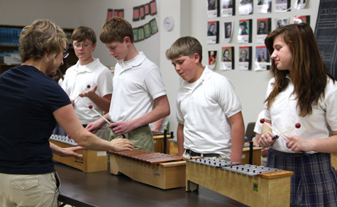 Dr. Liana Tyson shows eighth-grade students at Immaculate Conception School in North Little Rock what notes to play on their metallophones before recording their music video project.