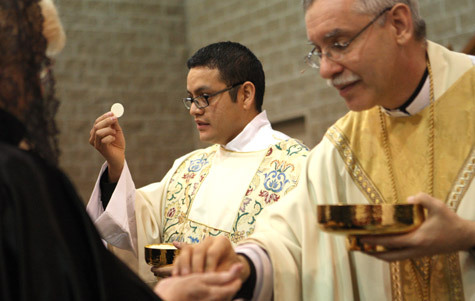 Deacon Juan Manjarrez distributes Communion during his diaconate ordination May 21, 2011, at the Fort Smith Convention Center.