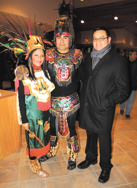 Father Juan Manjarrez poses with two members of his faithful flock following the Our Lady of Guadalupe procession. Maria Garcia and Mauricio Hurtado performed for the first time this year with the Aztec dancers.