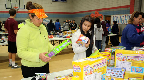 Lourdes Perez of Rogers (left), a mother of three children, peruses one of many tables of toys at the sixth annual Society of St. Vincent de Paul Toy Drive.