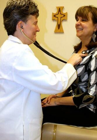 Sister Lisa Atkins, RSM, talks to her patient, Elsa Wood, as she listens to her heart in a routine exam. Sister Lisa has been working as a nurse practitioner in the Mercy System of Northwest Arkansas for the past nine years.