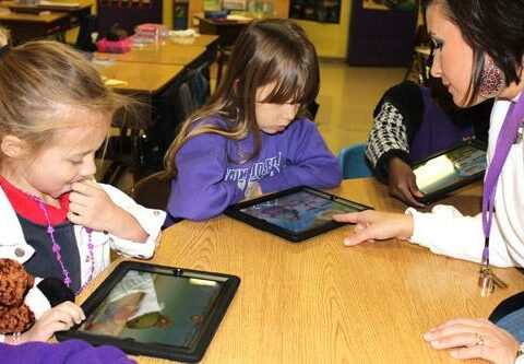 First-graders Avery Neal (left) and Cherokee Jones work on iPads during reading class under the watchful eye of their teacher, Courtney Pope. The children are students at St. Joseph School in Conway.
