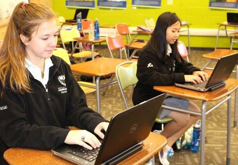Mount St. Mary Academy seniors Therese Dobry (left) and Duyen Ha work on their school-issued laptops. The school issues laptops to all incoming freshmen and the technology has made Cyber Day curriculum possible during bad weather.