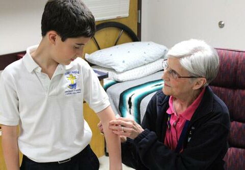 Billie Maxwell, school nurse at Immaculate Conception School in North Little Rock, applies a bandage and some TLC to fifth-grader Jacob Miller. Max-well has been school nurse there for seven years.