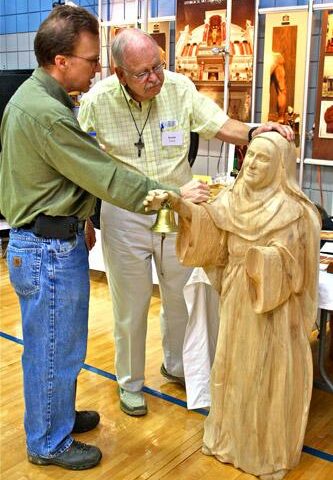 George Hoezelman, artist and owner of G.R. Hoezelman Studios (left) points out details of a wood carving of St. Anne to Kas Taylor, parishioner of St. Vincent de Paul in Rogers. Taylor was one of 550 attendees to the inaugural Ozark Liturgical Conference held in Rogers, Aug. 2. Alesia Schaefer photo