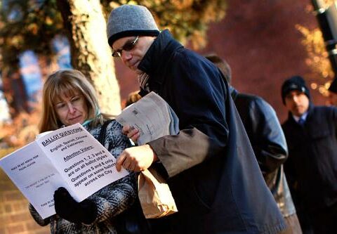 Voters in Boston look over information on ballot questions while waiting at a polling place in November 2012.
