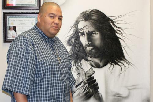 Jaime Torres, associate director of faith formation, stands by an airbrushed painting in his office at the diocese. The image of Jesus, created by a friend in Mexico, is used at Fuerza Transformadora events.