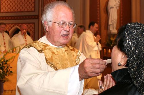 Msgr. Richard Oswald offers Communion at the jubilee Mass held at the Cathedral of St. Andrew in Little Rock June 30. A priest for 50 years, he suggest-ed young seminarians focus on building their prayer life.