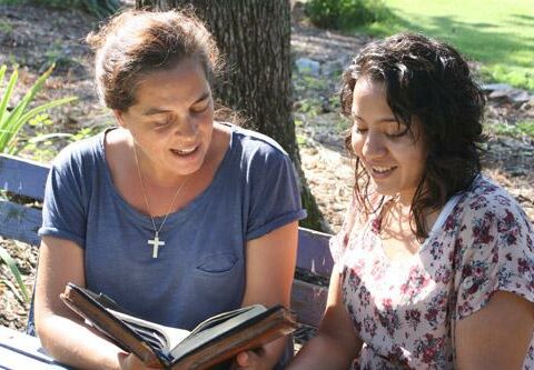 Traveling missionaries Maruxa Atienza (left) and Stephanie Rivera read from John 2, The Wedding at Cana, before starting their day of evangelization in Little Rock. The two came to the city with nothing but Bibles and the clothes on their backs.