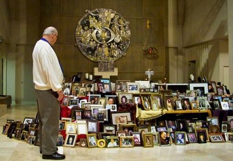 Dale Emmerling, a team volunteer for the Ministry of Consolation program, reflects on photos placed on the altar at Christ the King Church in Little Rock to commemorate All Souls Day.