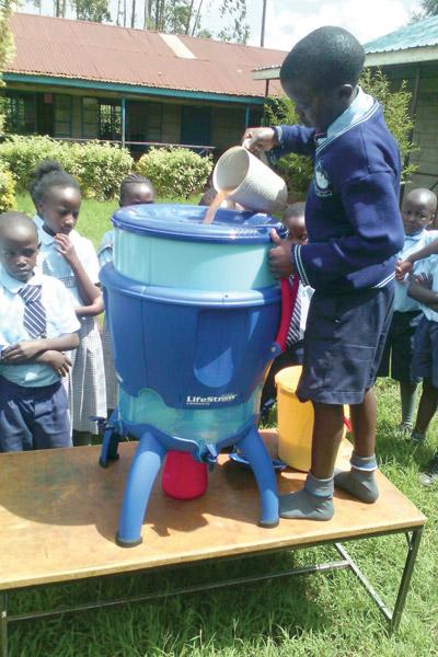 A student at Magutuini School outside Nairobi, Kenya, pours collected water into the LifeStraw Community filter purchased for the school by donations through Replenish, a ministry-based nonprofit.