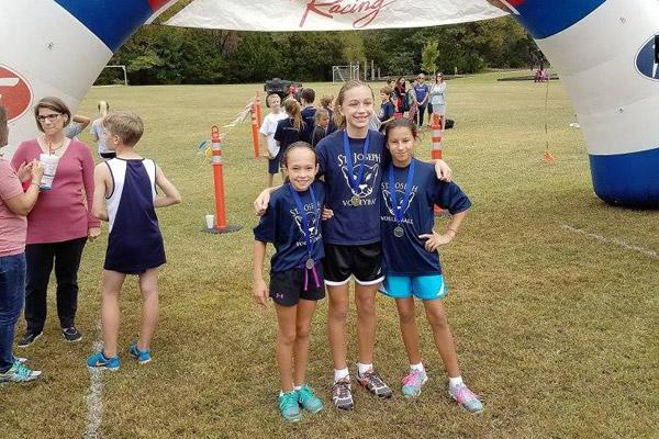 St. Joseph fifth-grader Karina Wilhelm (left) and sixth-graders Julia Gunnell and Kristina Keenan stand near the finish line at a cross country event for the Ozark Activities Conference.