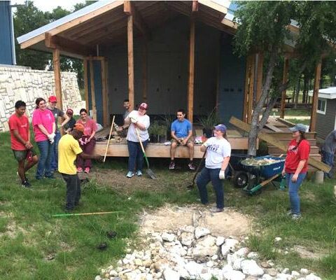 Students from Arkansas colleges attending a diocesan mission trip to Community First! Village in Austin, Texas, take a break from landscaping May 16 with resident John Francis (center left in yellow shirt).