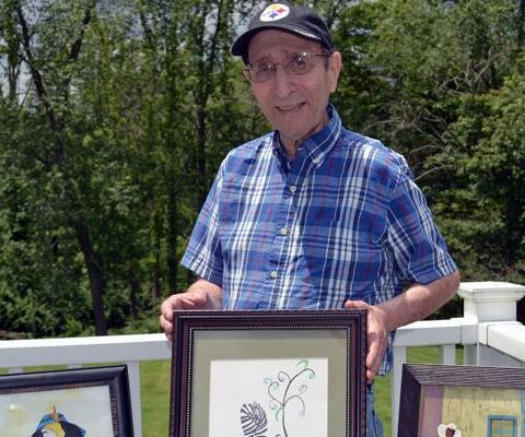 Father Ralph Esposito, retired pastor of St. Michael Church in Van Buren, stands with some of his watercolor paintings at his home in New Castle, Pa. He celebrated 50 years of ordination May 13.