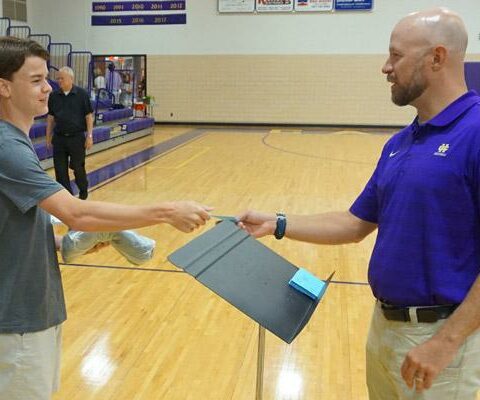 Catholic High assistant principal Matt Dempsey (right) hands a card to Ben Glassford, 17, during senior registration Aug. 4. Students can earn college credit during the school year with concurrent classes.