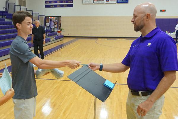 Catholic High assistant principal Matt Dempsey (right) hands a card to Ben Glassford, 17, during senior registration Aug. 4. Students can earn college credit during the school year with concurrent classes.