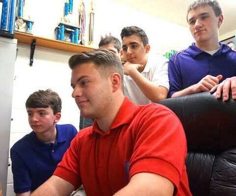 Catholic High senior Alex Clark pulls up an image on the computer used by the Cyber Defense team, while freshman Anthony Hailey (left), freshman Albert Isaac, junior Alex Bromley and other members watch. Team members compete in cyber security competitions.
