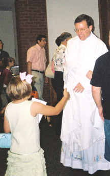 Father Michael Sinkler, pastor of St. Stephen Church in Bentonville, greets parishioners after a recent weekend Mass. Members will celebrate the pastor's 25th anniversary July 23.