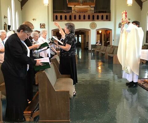 Father Les Farley, chaplain at St. Scholastica Monastery in Fort Smith, holds up the Book of Gospels during his 25-year jubilee Mass May 29 in the monastery chapel with the Benedictine sisters, friends and family.