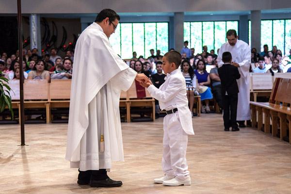 Angelo Figueroa, then 8 years old, receives first Communion from Father Juan Manjarrez at St. Vincent de Paul Church in Rogers in 2014. Right after receiving Communion, Figueroa, who was born with a brain disorder called agenesis of the corpus callosum, joyfully said &ldquo;I got it,&rdquo; Debbie Dufford said, who helps prepare those with special needs for the sacraments. (Paul Dufford photo)