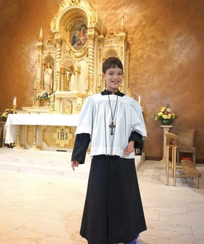 Grady Smith, 10, who has cerebral palsy, smiles in front of the altar at St. Mary Church in Hot Springs. He has been an altar server for about a year.