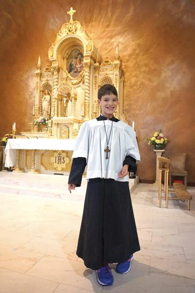 Grady Smith, 10, who has cerebral palsy, smiles in front of the altar at St. Mary Church in Hot Springs. He has been an altar server for about a year.