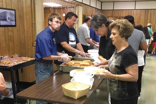 Kasen Goodwin, 22 (left), helps serve a meal to participants at a Knights of Columbus event this past spring. Goodwin, who has Asperger syndrome, is a member of the Knights and active in other parish activities.