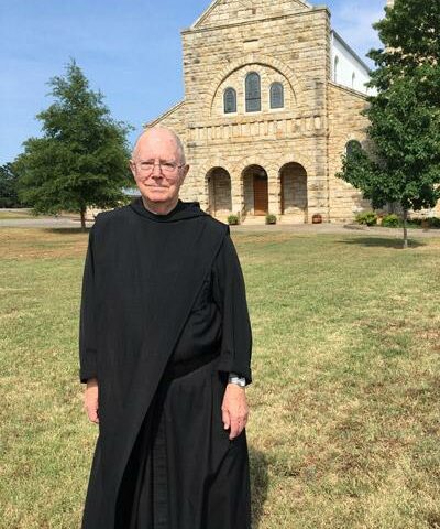 Father Hugh Assenmacher, OSB, stands in front of St. Mary Church in Altus where he is sacramental minister.