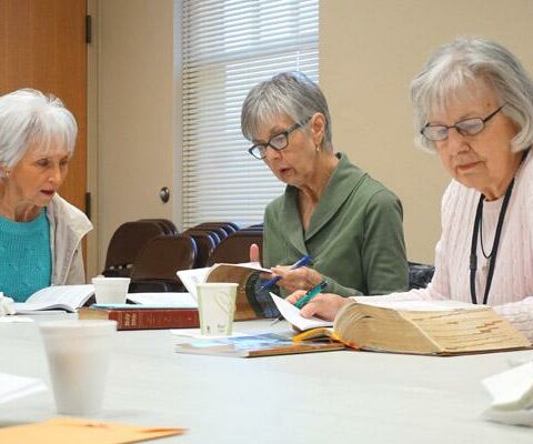 Sue Riggin (left) reads from Little Rock Scripture Study lessons while others, including Katie Hodge and leader Lilly Hess (right), listen during their Friday morning Bible study at Our Lady of the Holy Souls Church in Little Rock.