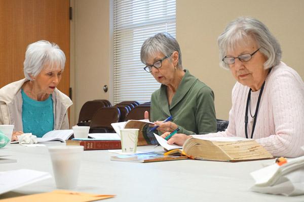 Sue Riggin (left) reads from Little Rock Scripture Study lessons while others, including Katie Hodge and leader Lilly Hess (right), listen during their Friday morning Bible study at Our Lady of the Holy Souls Church in Little Rock.