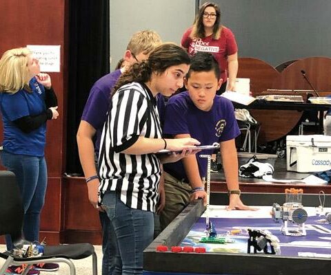 A judge in the regional competition looks over a robot brought by St. Joseph School in Paris as robotics team member Samuel Wu, 10, watches. The competition was held at the Springdale Don Tyson School of Innovation.