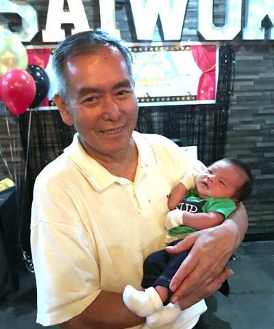 Bryan Nguyen holds his grandson, Teagan, at his retirement party in September 2018. Nguyen helped organize the first Vietnamese Mass at St. Vincent de Paul Church in Rogers.