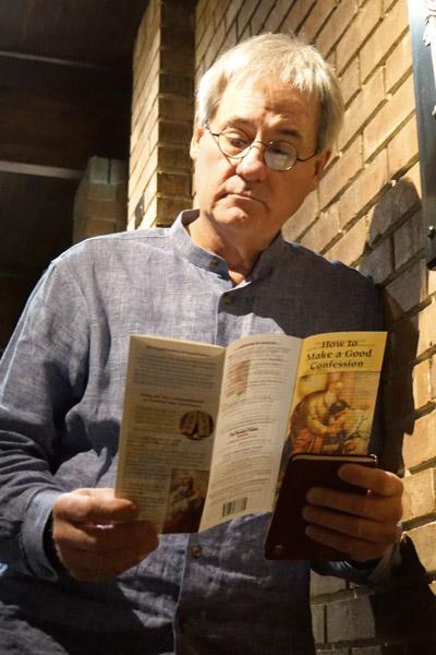Larry Witherspoon stands outside the confessional at Our Lady of the Holy Souls Church in Little Rock reading a pamphlet on how to make a good confession. Many parishes have similar materials available.