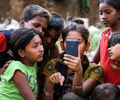 Indian children watch a movie on a cellphone on the roadside in Mumbai in 2016. While digital communications and social media can be used as a tool of evangelization and a place of dialogue with others, they also can be lonely environments where young people fall prey to humanity's worst vices, Pope Francis wrote in his new apostolic exhortation to young people, "Christus Vivit" ("Christ Lives").