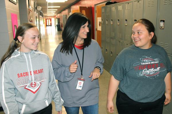 Jennifer Roscoe, counselor at Sacred Heart School in Morrilton, catches up with ninth-graders Karlee Cooper (left) and Maggie Lentz between classes. Roscoe said students everywhere face the same pressures and challenges.