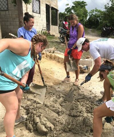 University of Arkansas students, on a mission trip to the Dominican Republic, work on building a house for an employee of NPH. Students mix each batch of concrete by hand.