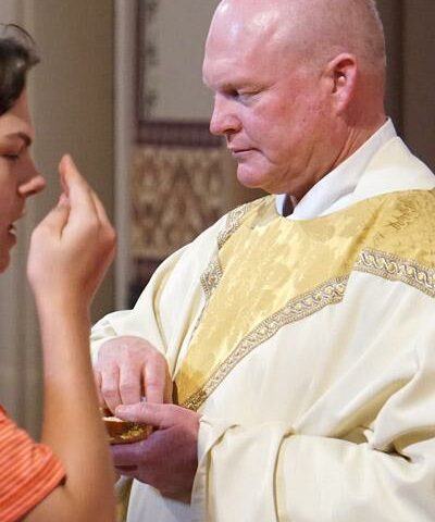 Father Phillip Reaves gives Communion during the priest Jubilee Mass, June 25, at the Cathedral of St. Andrew in Little Rock. Father Reaves, diocesan director of prison ministry, was the only jubilarian this year, celebrating 25 years of priesthood May 21.