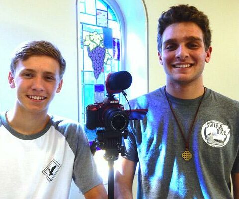 Collin Gallimore (left) and Anthony Reiter stand with a camera at St. Mary of the Springs Church Parish Hall.