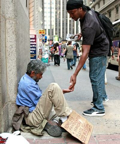 A pedestrian gives money to a homeless man outside St. Francis of Assisi Church in New York City. Almsgiving, donating money or goods to the poor and performing other acts of charity, is one of the three pillars of Lent.