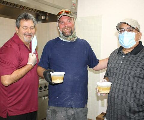Michael Young, grand knight of the Knights of Columbus at St. Bernard Church in Bella Vista, helps Jeff Wetzel and Mario Eschavarria prepare meals to be delivered to the homebound of the parish Aug. 6.