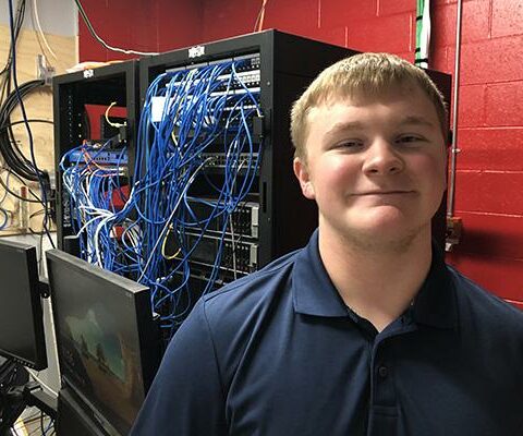 Thomas Buser, 18, smiles in the server room at Sacred Heart High School
in Morrilton May 10. Since sixth grade, he has helped the school with IT
support and setting up networks.