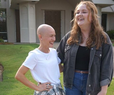 Karly Brooks, who wears her head shaved, laughs with Kenzie Cundall outside Christ the King Church in Little Rock Aug. 13. The friends recently started a young adult group for the parish that meets monthly.
