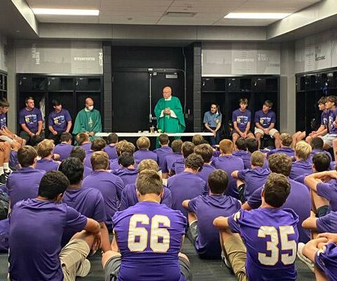 Rector Msgr. Lawrence Frederick (center) celebrates Mass with chaplain Father Patrick Friend for the Catholic High football players before their Catholic Bowl game Sept. 4.