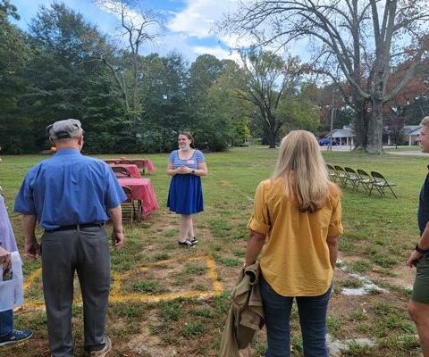 Campus minister Kasey Miller leads guests on a "tour" of the proposed new campus ministry building in Conway Sept. 18. Wall positions of the planned building were painted on the ground, allowing donors to envision the space.