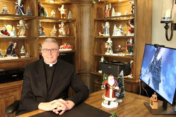 Father John Connell sits in his office decorated for Christmas Dec. 7. An auction of many of his items from his extensive Christmas collection will be auctioned off in July to benefit St. Raphael Parish in Springdale.